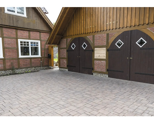 Einfahrt mit Pflastersteinen vor einem Haus mit Holztor und Holzelementen