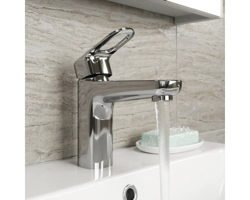 Glänzender Waschtischmischer aus Metall auf einem Waschbecken mit fließendem Wasser