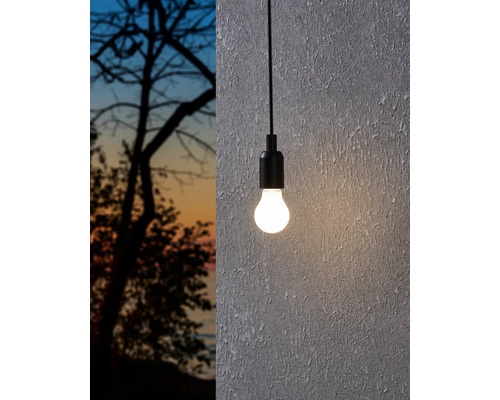 Hängelampe mit Glühbirne vor einer Wand