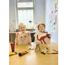Zwei Kinder präsentieren stolz ihre mit Farbe gemalten Bilder.