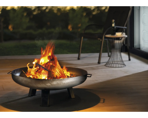 Feuerschale mit brennendem Holz auf einer Terrasse mit Sitzgelegenheiten