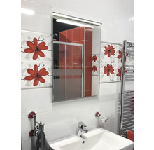 Helles Badezimmer mit Waschbecken, beleuchtetem Spiegelschrank und floralen Fliesen