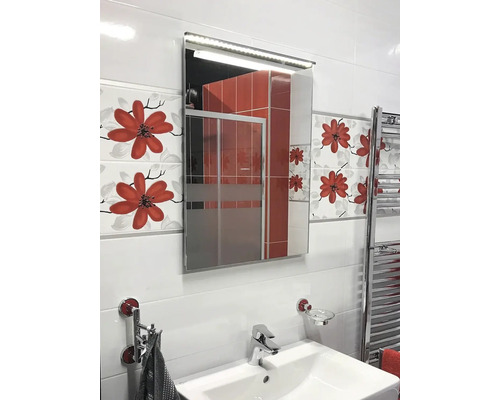 Helles Badezimmer mit Waschbecken, beleuchtetem Spiegelschrank und floralen Fliesen