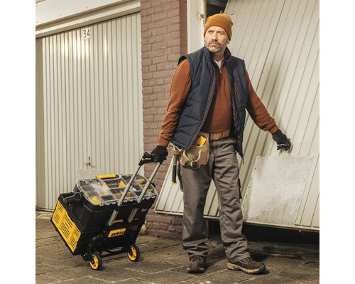 Handwerker mit Werkzeugwagen vor einer Garage