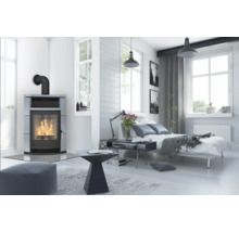 Helles Schlafzimmer mit Kaminofen, Bett und Fenstern für eine freundliche Atmosphäre.