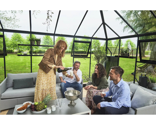 Szene in einem Gewächshaus mit einer Gruppe von Menschen, die an einem Tisch sitzen und Getränke genießen