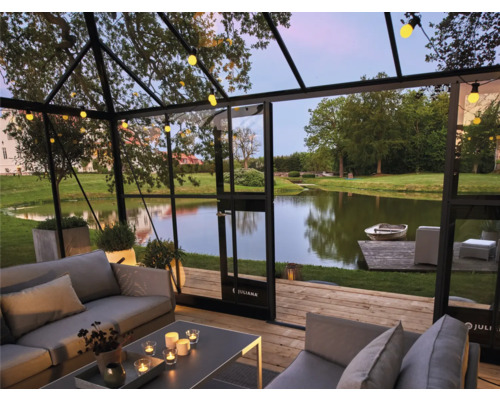 Innenansicht eines Gewächshauses mit Sitzgelegenheiten und Blick auf einen See