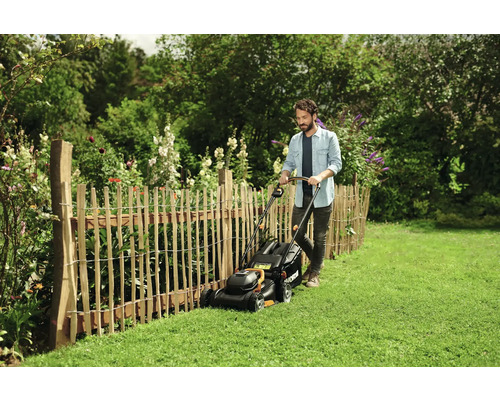 Mann mäht Rasen mit einem Rasenmäher in einem Garten