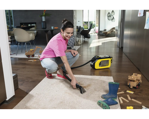 Frau reinigt Teppich mit einem Waschsauger in einem Wohnzimmer