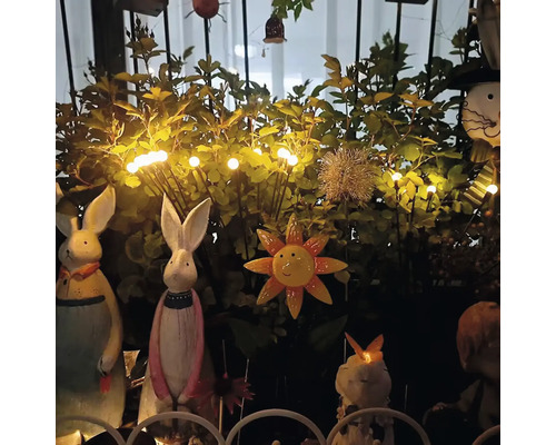 Dekorative Gartenszene mit Hasenfiguren, Sonnenblumenornament und Lichterkette