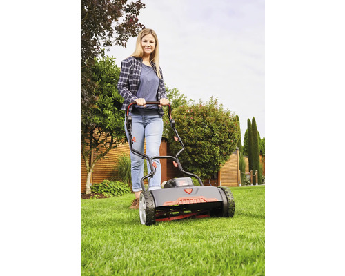 Frau bedient Spindelmäher im Garten.