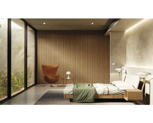 Helles Schlafzimmer mit Bett, Sessel, Lampe und großem Fenster mit Blick ins Grüne.