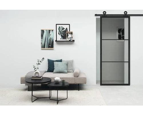 Wohnzimmer mit Schiebetür, Sofa, Couchtischen und Wanddekorationen.