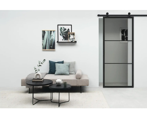 Wohnzimmer mit Sofa, Couchtischen, Wanddekoration und Glasschiebetür