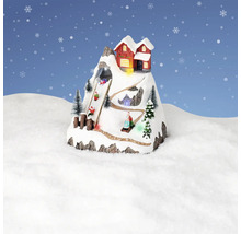 Dekorative Winterlandschaft mit Berghaus und Schlittenfahrern