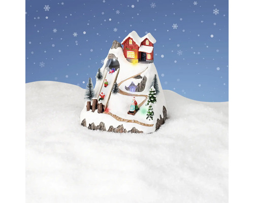 Dekorative Winterlandschaft mit Berghaus und Schlittenfahrern