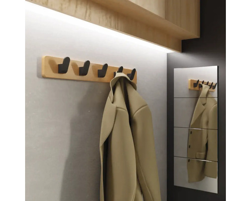Garderobe mit Holzbrett und mehreren Haken, daneben ein Spiegel mit Reflektion einer Jacke