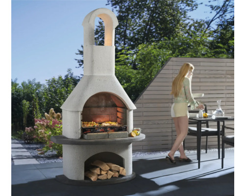 Gemauerter Gartengrill mit Holzscheiten und Frau im Garten