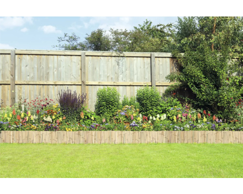 Gartenszene mit Holzzaun, Blumenbeet und Bambuseinfassung