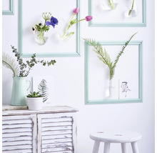 Dekorative Szene mit Blumen in Rahmen an einer Wand, Kommode und Hocker