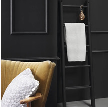 Dekorative Szene mit Leiter, Handtuch, Sessel und Kissen vor dunklem Hintergrund.