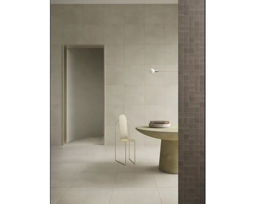Heller Raum mit Fliesen an Wand und Boden, minimalistischem Stuhl und rundem Tisch