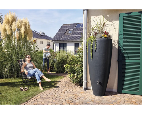 Szene im Garten mit Regentonne, Mann beim Gießen und Frau im Liegestuhl