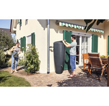 Personen nutzen eine Regentonne zur Gartenbewässerung in einem sonnigen Garten.