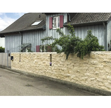 Eine Mauer aus Natursteinen vor einem Wohnhaus.