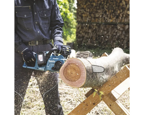 Mann sägt Holzscheit mit einer Akku-Kettensäge von Makita