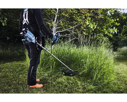 Eine Person arbeitet mit einem Akku-Rasentrimmer im Garten.