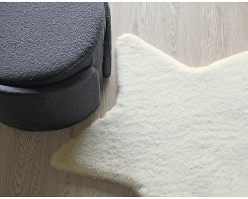 Dekoratives Arrangement mit einem grauen Hocker und einem weißen Sternteppich