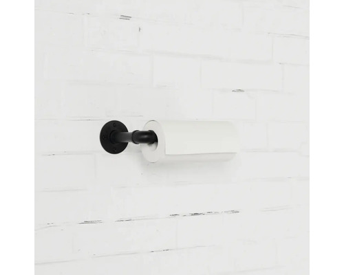 Schwarzer Toilettenpapierhalter mit Papierrolle an einer weißen Ziegelwand