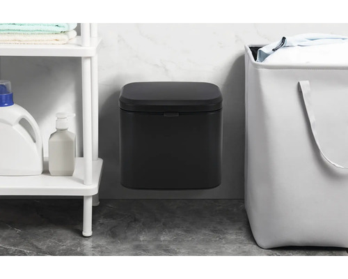 Wandmontierter Abfallbehälter neben einem Wäschekorb und einem Regal