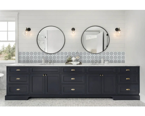 Badezimmer mit blauem Waschtischunterschrank, zwei runden Spiegeln und gemusterten Fliesen