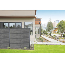 Modernes Haus mit grauer Betonzaun-Einfriedung zum Garten