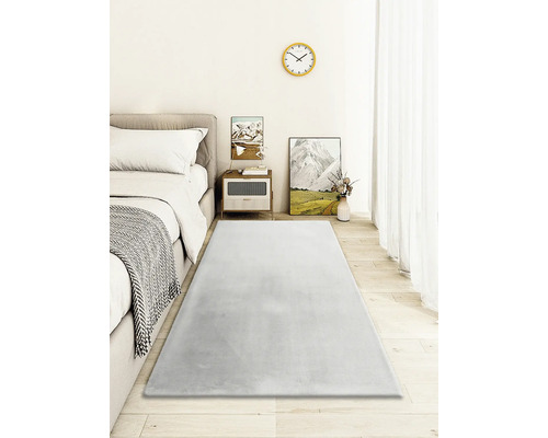 Schlafzimmer mit Bett, Nachttisch und grauem Teppich auf Holzboden.
