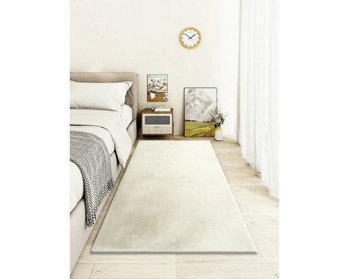 Helles Schlafzimmer mit Bett, Nachttisch und langem, rechteckigem Teppich