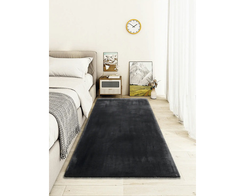 Schlafzimmer mit Bett, Nachttisch und dunkelgrauem Teppich