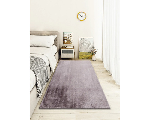 Schlafzimmer mit Bett, Nachttisch und lila Teppich