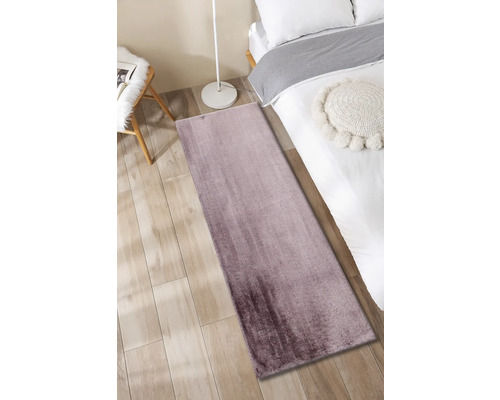 Moderner Teppich im Schlafzimmer auf Holzboden neben Bett und Lampe