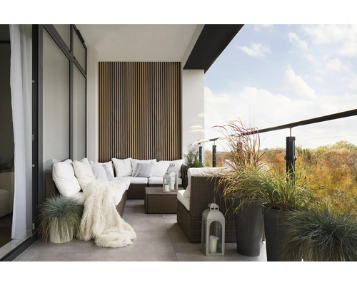 Balkon mit Rattansofa, Kissen, Decke, Laternen und Pflanzen in Töpfen