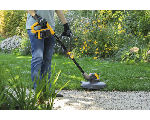 Person benutzt Rasentrimmer im Garten