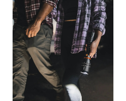 Eine Person hält eine leuchtende Taschenlampe in der Hand, während eine andere Person daneben steht