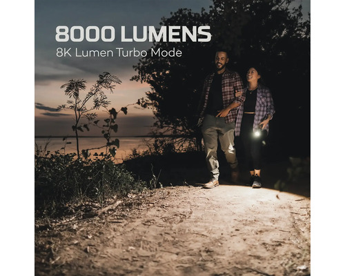 Ein Paar geht mit einer Taschenlampe auf einem Feldweg entlang, die 8000 Lumen im Turbo-Modus leuchtet.