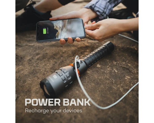 Eine Person lädt ein Smartphone mit einer Powerbank-Taschenlampe auf einem Felsen auf.