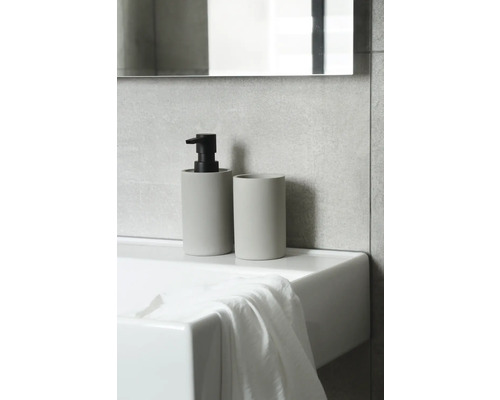 Seifenspender und Zahnputzbecher auf einem Waschbecken im Badezimmer.