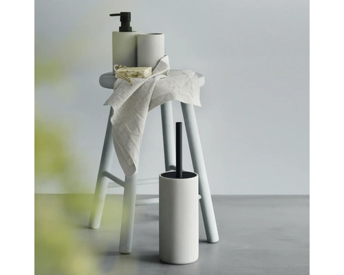 Badezimmerzubehör-Set mit Seifenspender, Becher, Seife, Handtuch und Toilettenbürste auf einem Hocker