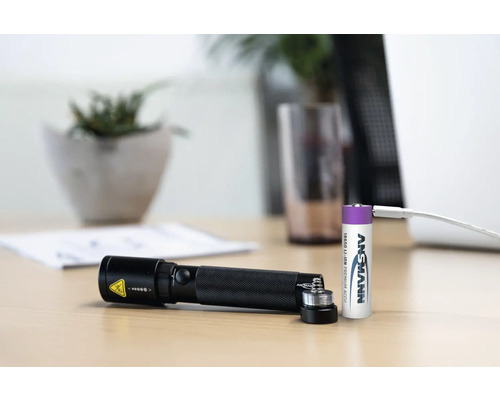 Schwarze Taschenlampe mit Akku und Ladekabel auf einem Tisch