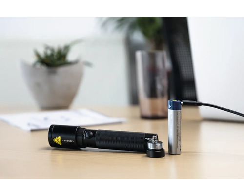 Akku Taschenlampe mit Akku und Ladekabel auf einem Tisch